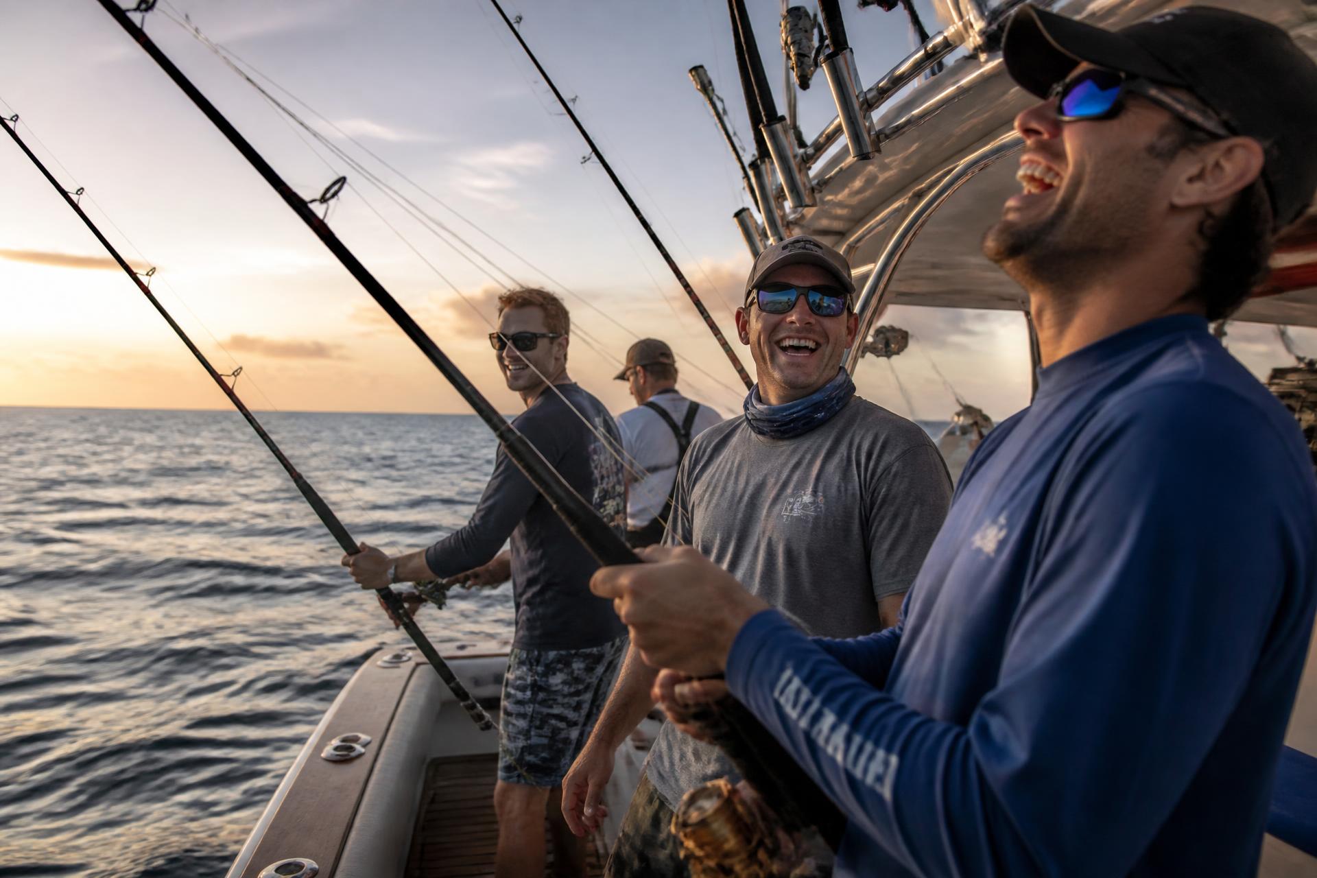 A group of men friends fishing from a luxury sportfishing yacht offshore at sunrise